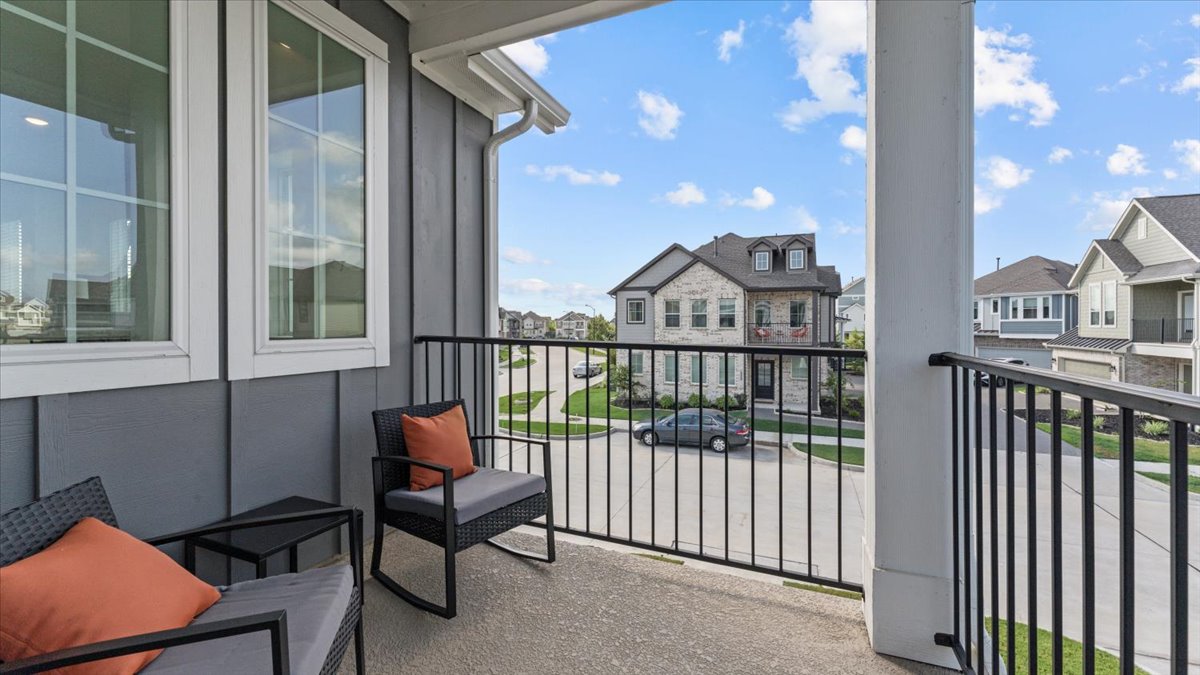 Private balcony with comfortable chairs and cushions, part of a furnished home rental in Cypress Texas.